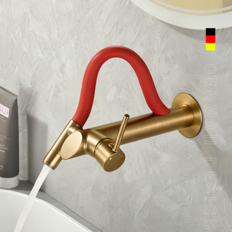 German design wall-mounted bathroom faucet in premium brushed gold featuring a vibrant red flexible silicone neck, single lever handle, running water into a white basin.